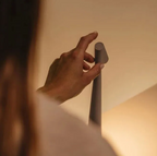 Hand using the circular top touch control on the angled lamp head