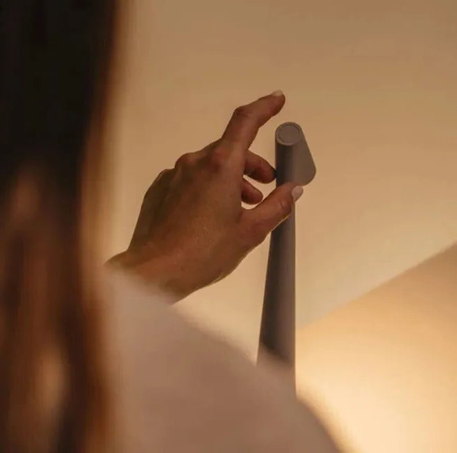 Hand using the circular top touch control on the angled HaloStem lamp head